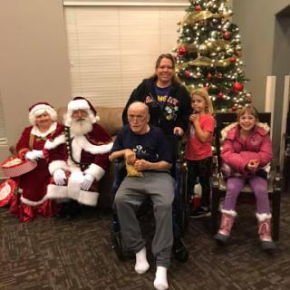 A joyful holiday gathering with Santa Claus, families, and children by the Christmas tree.