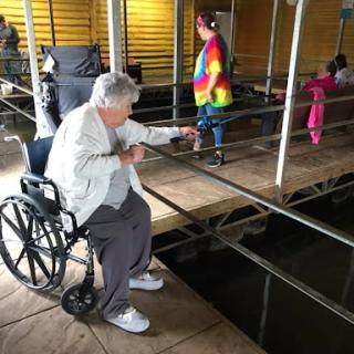 An elderly woman in a wheelchair interacts with children in an indoor setting.