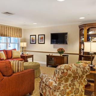 A cozy living room with a sofa, armchairs, and a television.
