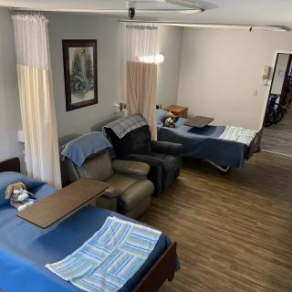 A healthcare facility room with multiple beds and privacy curtains.