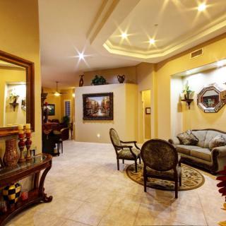 A spacious and elegantly decorated living room featuring comfortable seating, warm lighting, and artistic decor.