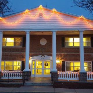 A beautifully illuminated building with a classic architectural design featuring columns and a porch at night.