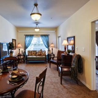 A cozy and elegantly decorated living room with a dining area, featuring comfortable seating, stylish lamps, and decorative curtains.