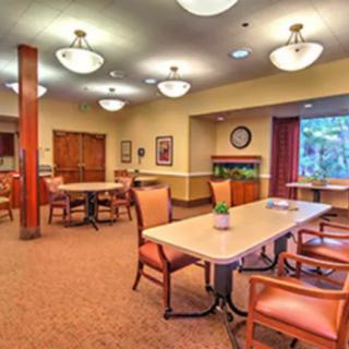 A well-lit dining area with multiple tables and chairs, decorated in warm tones.