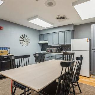 A kitchen with a dining table and chairs, featuring cabinets and a refrigerator.