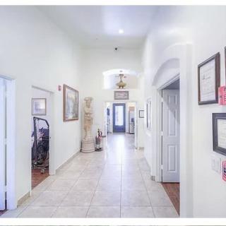 A bright hallway with tiled flooring and decorated walls, leading to multiple rooms.