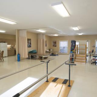 A spacious physical therapy room equipped with exercise bars and rehabilitation tools.