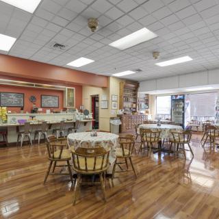An empty cafeteria with wooden floors, tables, and chairs.