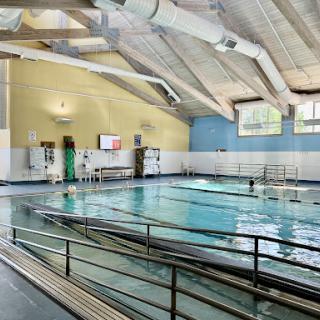A spacious indoor swimming pool with natural light illuminating the area, featuring multiple lanes for swimming and a serene atmosphere.