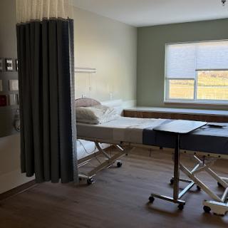A well-lit hospital room featuring a patient bed, privacy curtains, and a window.