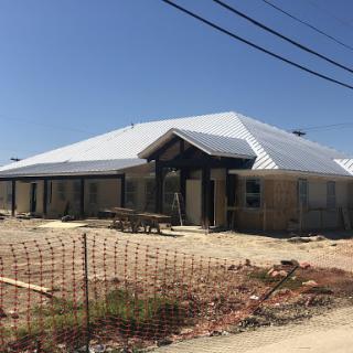 A newly constructed residential building with a metal roof, still in the early stages of completion.