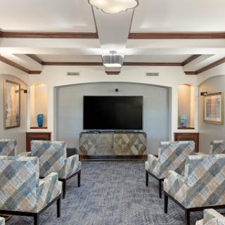 A modern lounge area featuring comfortable seating and a large television.