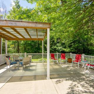A sunny outdoor deck with a covered seating area and lush trees in the background.