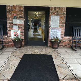 Entrance to a welcoming building with rocking chairs and potted plants.