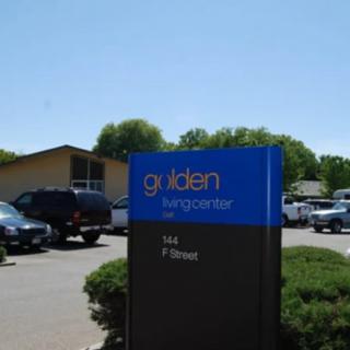 A building with a parking lot and a sign reading 'golden landscape co' on a clear day.