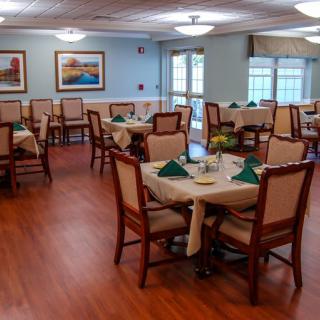A neatly arranged dining room with tables and chairs, featuring elegant decor and wooden flooring.