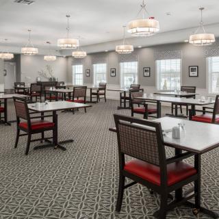 A spacious and elegantly decorated dining room with neatly arranged tables and chairs under modern chandeliers.