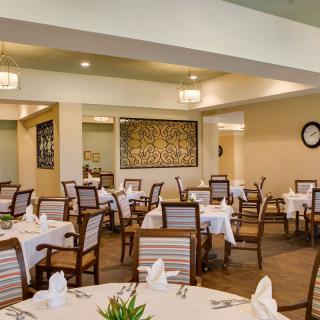 An elegant restaurant interior with neatly arranged tables and chairs, featuring white tablecloths and decorative napkins.