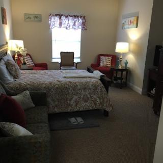 A cozy bedroom featuring a neatly made bed, comfortable seating, and warm lighting.