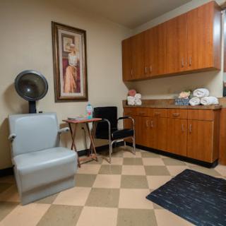 A cozy medical room featuring wooden cabinets, a hair dryer, and seating for patients.
