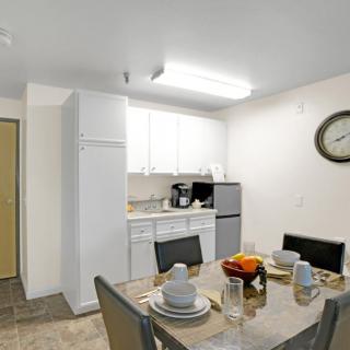 A modern kitchen and dining area with a fully set dining table, appliances, and a wall clock.