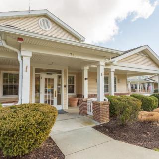 A suburban-style building entrance with a covered porch and landscaped surroundings.
