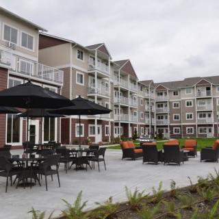 A modern apartment complex featuring outdoor seating and patio amenities.