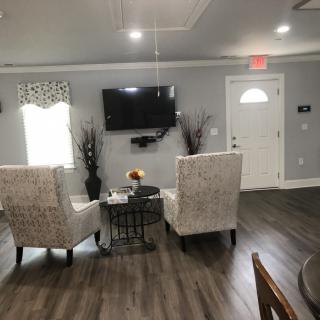 A modern living room with two upholstered chairs, a mounted television, and wood flooring.