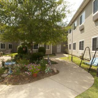 A peaceful courtyard with a garden and benches surrounded by a building.