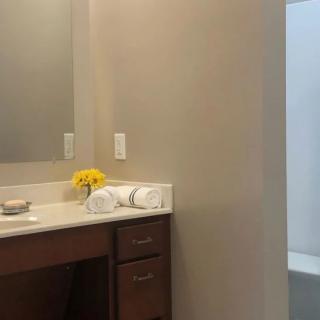 A clean and modern bathroom with a vanity, mirror, and fresh towels.