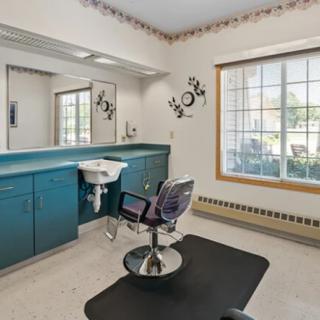 A well-lit hair salon interior with a styling chair, mirror, and sink.