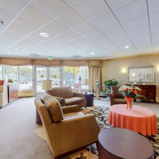 A cozy lounge area featuring comfortable seating, a coffee table, and large windows that allow natural light to fill the space.