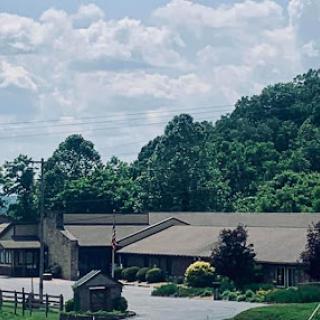 A serene view of a building nestled in a lush landscape under a cloudy sky.