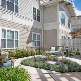 A cozy outdoor patio area with seating, surrounded by well-maintained landscaping in a residential building setting.