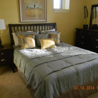 A cozy bedroom with a neatly made bed, decorative pillows, and warm lighting.