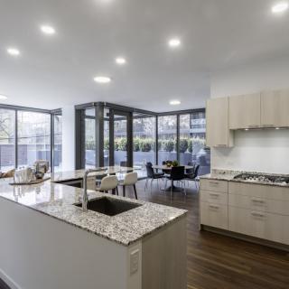 A modern kitchen with an open layout, featuring ample natural light and a central island countertop.