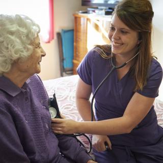 A nurse conducting a medical checkup on an elderly patient at home.