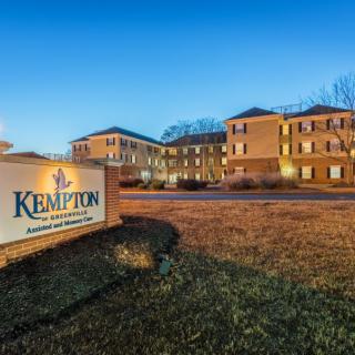 Exterior view of a hotel building with a sign reading 'Kempton' at twilight.