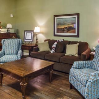 A cozy living room with a brown sofa, two patterned armchairs, and a wooden coffee table.