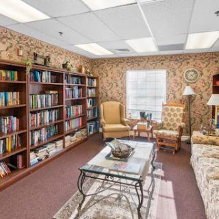 A cozy office space featuring a small library area with bookshelves, comfortable seating, and warm lighting.