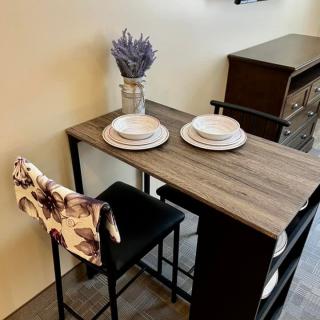 A cozy dining setup featuring a wooden table with two plates and a vase of lavender.