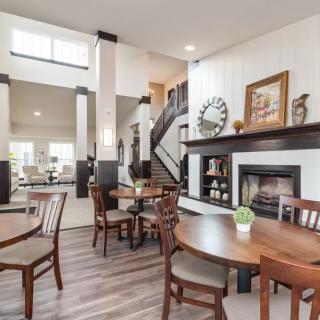 A modern living and dining area with neutral tones, featuring a cozy fireplace and wooden furniture.