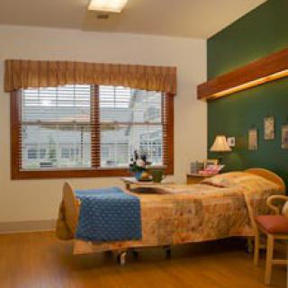 A cozy hospital room with a single bed and large window.