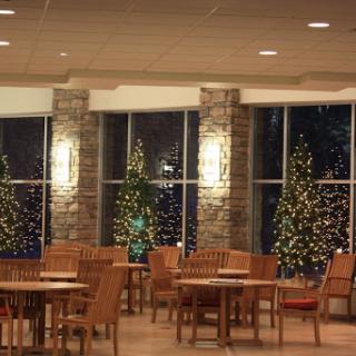 A cozy dining area decorated for the holiday season, featuring beautifully lit Christmas trees by the window.