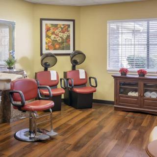 A cozy hair salon with red chairs, hair dryers, and wooden flooring.