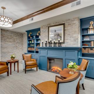 A cozy living room with a blue accent fireplace, surrounded by bookshelves and comfortable seating.