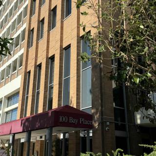 A city hotel building with a modern facade and trees in the foreground.