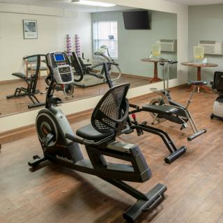 A small gym with exercise equipment including a treadmill and stationary bike, featuring mirrors on the walls.