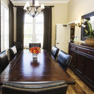 A well-decorated dining room featuring a long wooden table, leather chairs, and a chandelier.