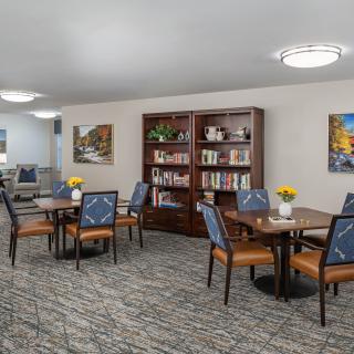 A cozy library area featuring bookshelves, tables, and chairs with modern lighting.